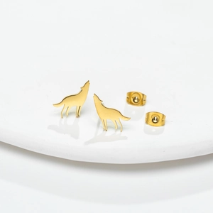 Macro view of gold wolf stud earrings with matching butterfly backs on a ceramic tray