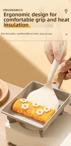 Spatule en silicone à manche en bois retournant une omelette dans une poêle à tamagoyaki
