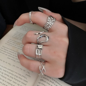 Silver geometric irregular rings set shown stacked against an artistic book background