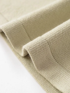 Vista macro dettagliata della trama del tessuto in maglia beige con punti di sutura fini