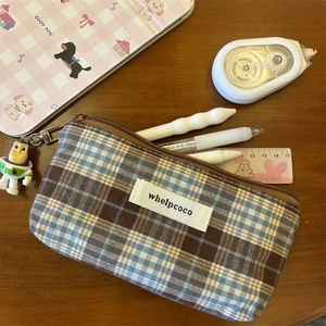 Macro view of vintage plaid canvas pouch with character charm and metal zipper detail