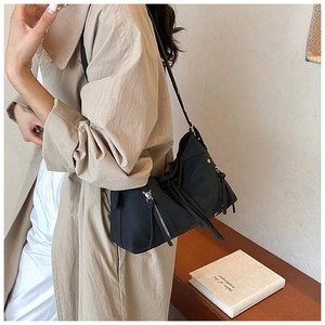 Dettaglio della borsa a tracolla nera stile biker con zip e frange lunghe argentate