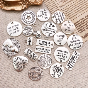 Macro view of vintage silver DIY charms with motivational quotes on rustic linen