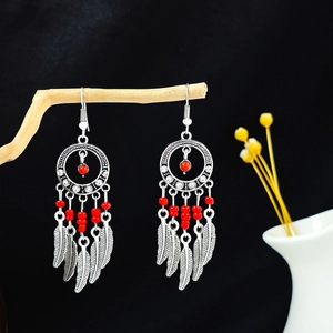 Détail de boucles d'oreilles attrape-rêves bohèmes avec perles rouges et plumes