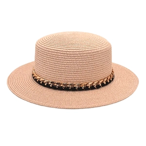 Détail d'un chapeau de paille d'été avec chaîne dorée et texture tressée élégante