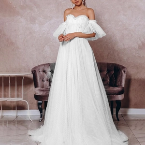 Elegant white off-shoulder bridal gown with polka dot tulle and tiered ruffle sleeves