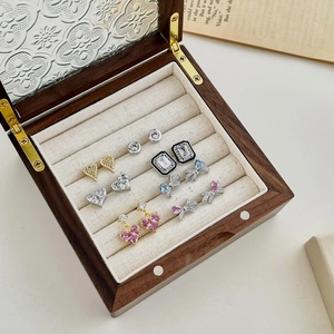 Detail view of a luxury wooden jewelry box with blue heart earrings and velvet slots