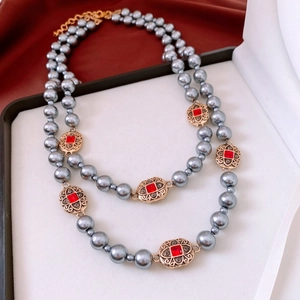 Detail of vintage necklace set featuring grey pearls and red gemstone in a gold setting
