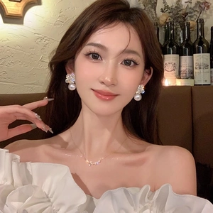 Detailed view of pearl snowflake earrings and fine diamond necklace on model