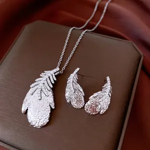 Luxury silver feather jewelry set with zircon crystals on premium display leather