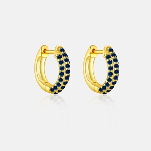 Close-up of gold hoop earrings with pavé set blue stones and mirror reflection
