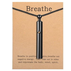 Detail of black mindfulness breathing whistle pendant with triangle cutout on a gift card