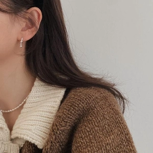 Detail of silver bead pendant earring styled with a pearl necklace and brown knit sweater