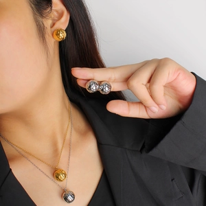 Close-up of gold and silver soccer ball pendant necklace and earrings worn by a model