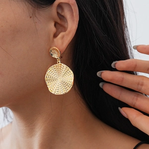 Close-up of gold-finish geometric hoop earring with woven texture shown on a model