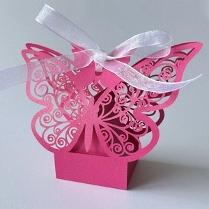 Close-up of pink laser-cut butterfly candy box with white organza ribbon for weddings