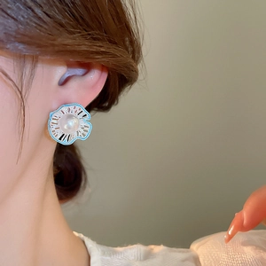 Close-up of a floral pearl stud earring with blue enamel detailing on a model ear