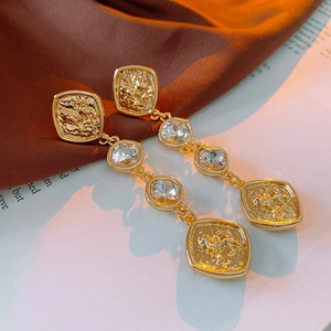 Detail of vintage gold-plated drop earrings featuring embossed metal and clear crystals