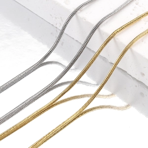 Polished gold and silver stainless steel snake chain necklaces displayed on white stone