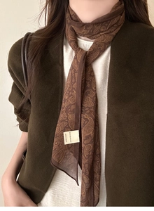 Detail of soft dark brown paisley silk scarf necklace with elegant retro pattern texture