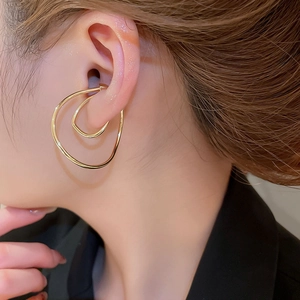 Close-up of a model wearing the irregular twisted gold ear cuff with minimalist curves