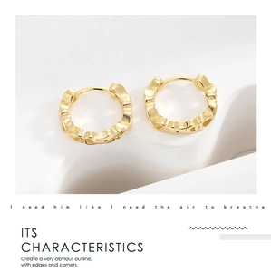 Detailed macro view of gold-plated geometric heart earrings on a white stone base