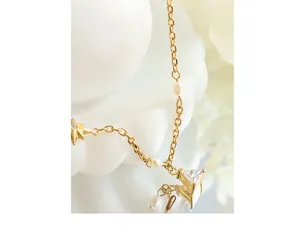 Detail of gold star necklace with triangle zircon and pearl accents on mirror