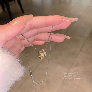 Dettaglio del ciondolo con anelli intrecciati in oro e argento su una catena sottile
