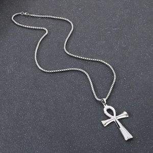 Detailed view of silver Ankh cross pendant and box chain on a stone texture background