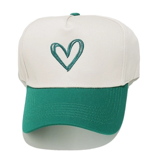 Close-up of green heart embroidery on a cream and green panel trucker baseball cap