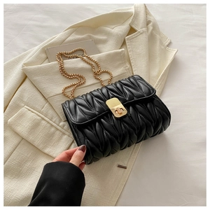 Macro detail of black matelassé quilted chain bag with elegant gold twist-lock closure