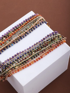 Close-up of multi-colored natural stone beaded necklaces with gold spacer beads on brown background