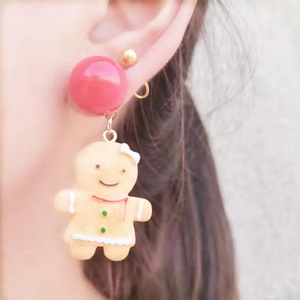 Close-up of cute Christmas gingerbread man earrings worn on ear with red bead detail