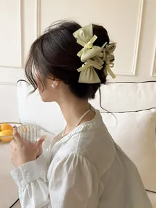 Detail of elegant satin multi-layer bow hair claw clip in cream worn by a model