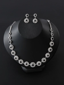 Close-up of bridal necklace and earrings set with black gems and silver plating