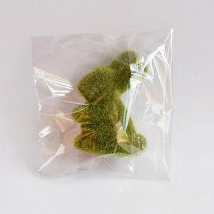 Detailed macro view of green artificial moss rabbit figurine inside protective packaging