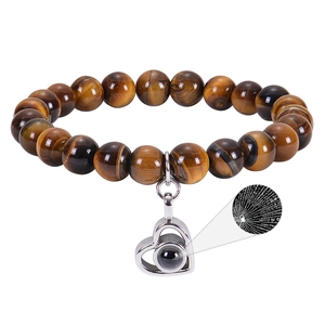 Close-up of tiger eye stone bracelet with heart projection charm on white background