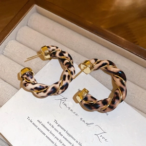 Detail view of leopard print hoop earrings with gold wire wrap in a beige jewelry box
