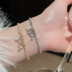 Detail of adjustable zircon fleur-de-lis cross bracelets with pearls in gold and silver