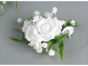 Detailed view of white silk rose boutonniere with green leaves and metal clip