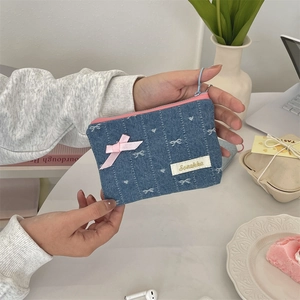 Detail of denim coin purse with white bow embroidery and pink satin ribbon accent