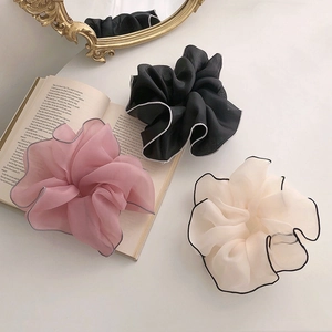 Detailed macro view of large mesh hair scrunchies in black, pink and beige tones
