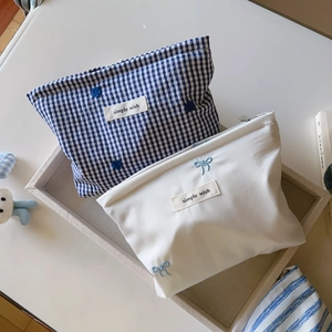 Detail of blue striped and white embroidered bow makeup bags with simple wish label
