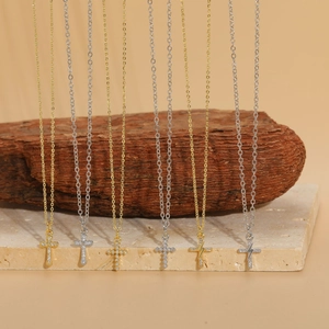 Close-up of minimalist cross and lightning bolt pendants with zircon on delicate chains