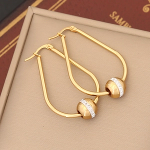 Macro detail of gold U-shaped drop earrings with sparkling pavé crystal bead charms
