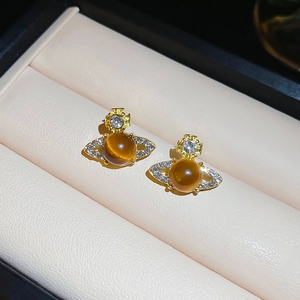 Macro shot of gold planet stud earrings with amber bead and crystals in a jewelry box