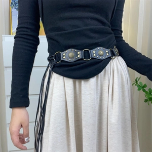 Detail of Y2K vintage black PU leather belt with metal rivets and long fringe tassels