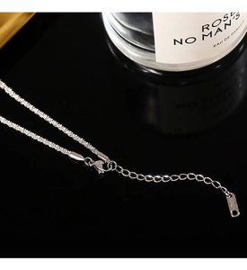 Macro detail of silver titanium lobster clasp with 18KGP engraving and extension chain