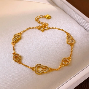 Bracelet doré avec pendentifs calebasse, pièces et zircons sur un support de bijoux