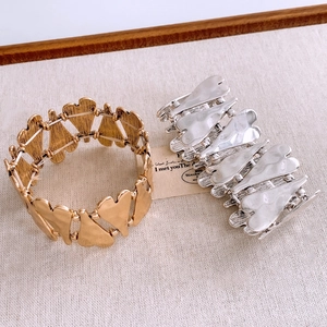 Detailed shot of gold and silver heart-shaped elastic bracelets with brushed metal texture